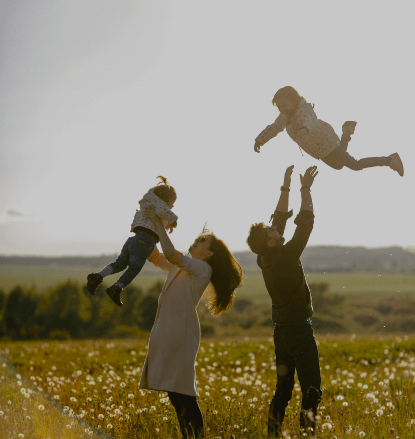 Family playing outdoors - Parents lifting child in the air